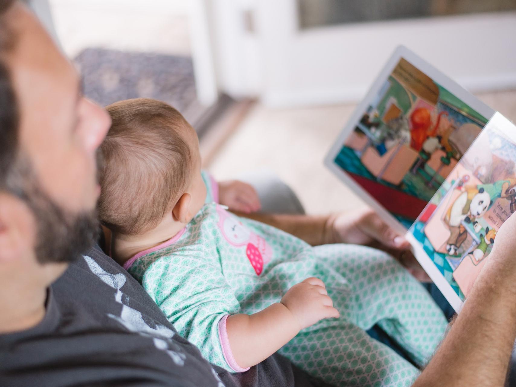 person carrying baby while reading book